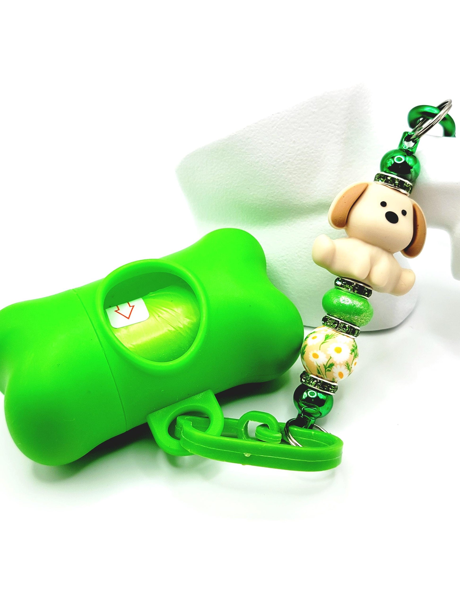 Green dog training clicker with a decorative keychain on a white background