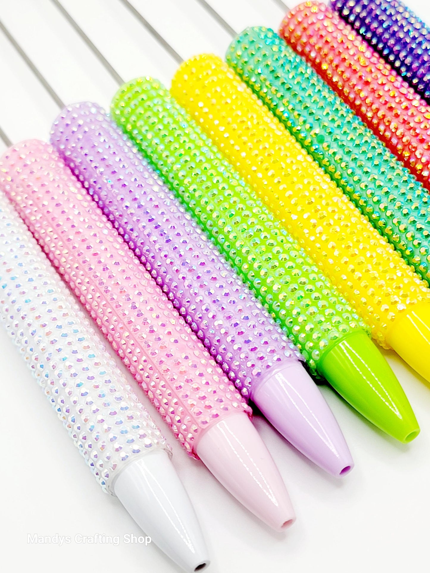 Colorful pen caps with rhinestone embellishments on a white background