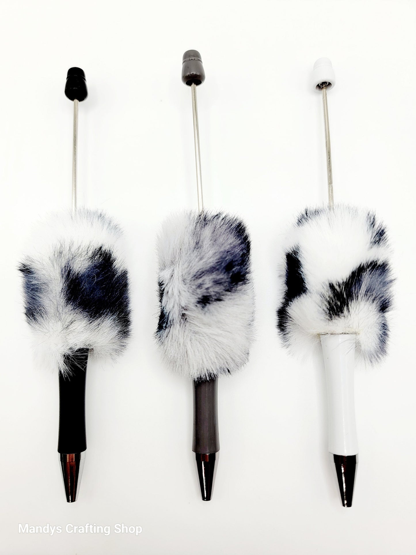 Three decorative pens with fur accents on a white background