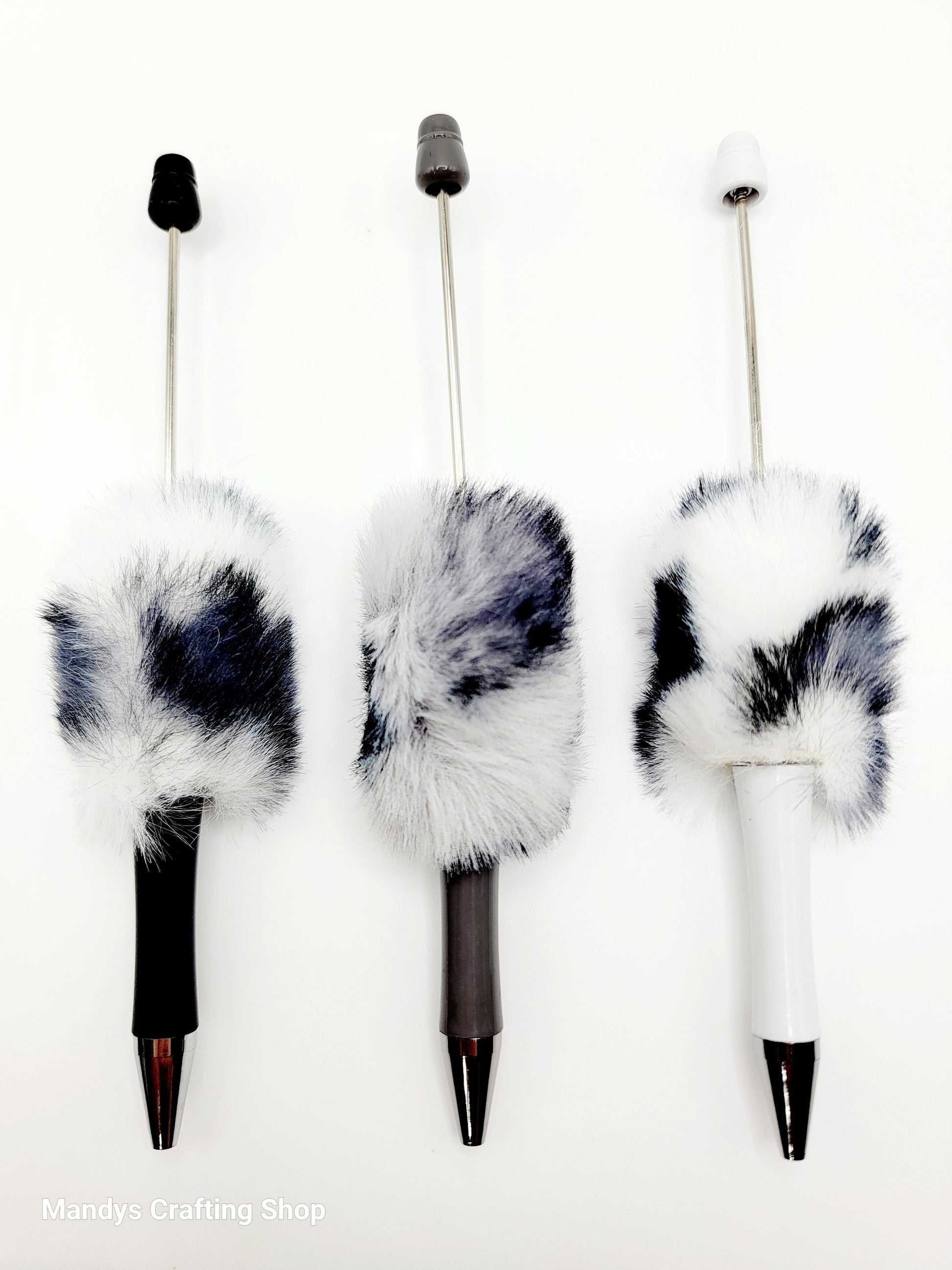 Three decorative pens with fur accents on a white background