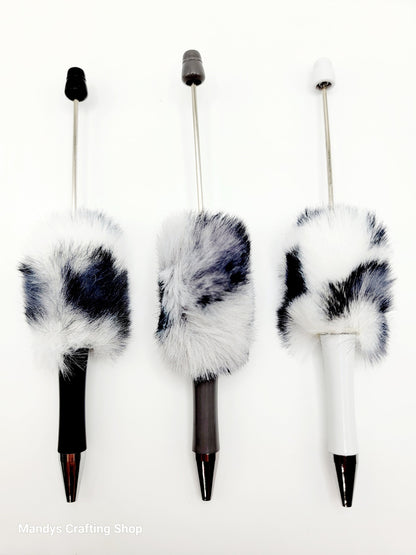 Three decorative pens with fur accents on a white background