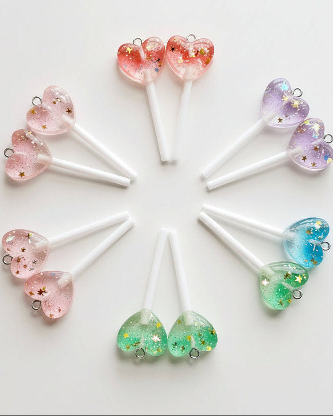 Heart-shaped lollipop charms on white sticks with a white background