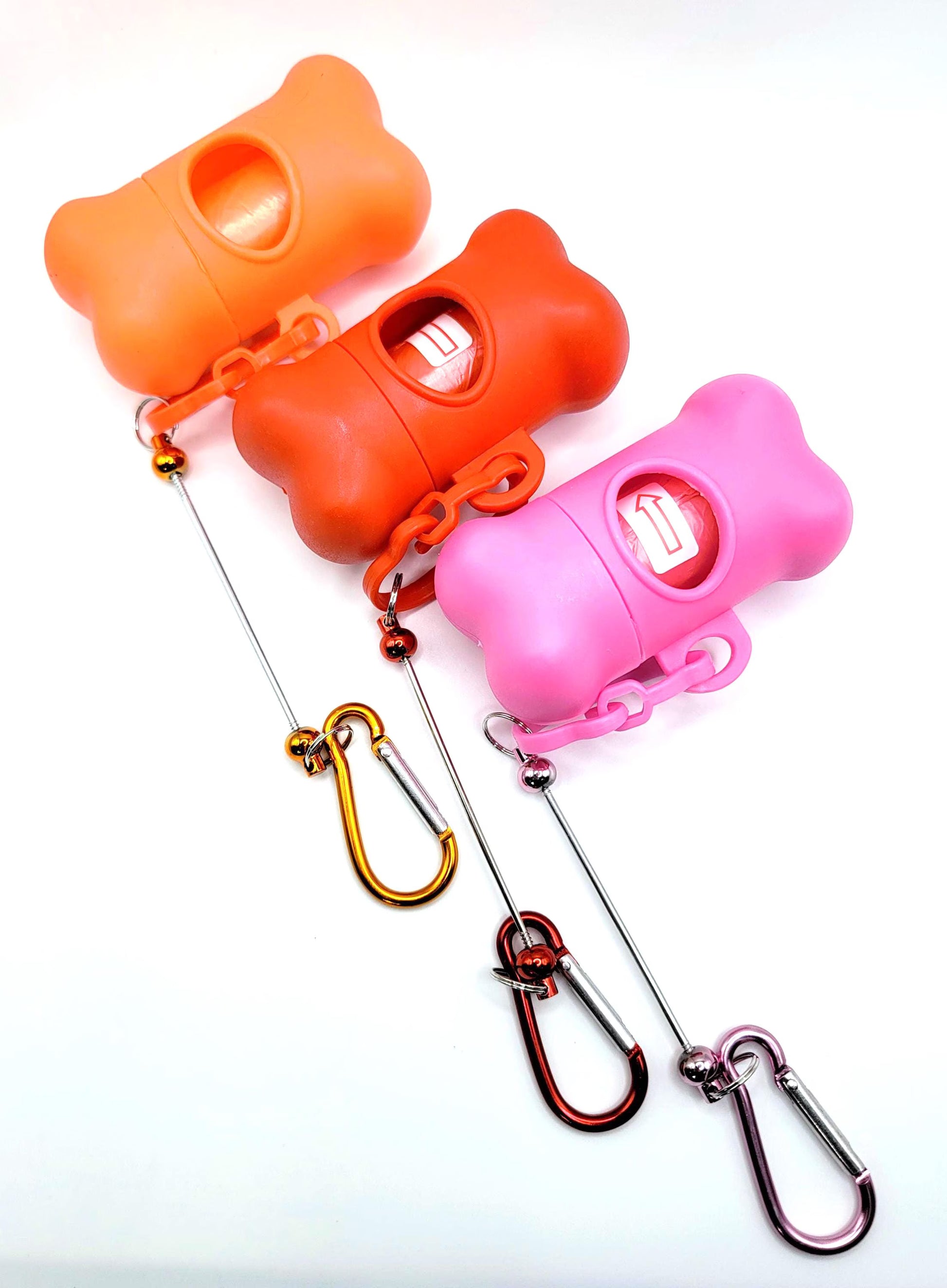 Three colorful dog training clickers with carabiners on a white background